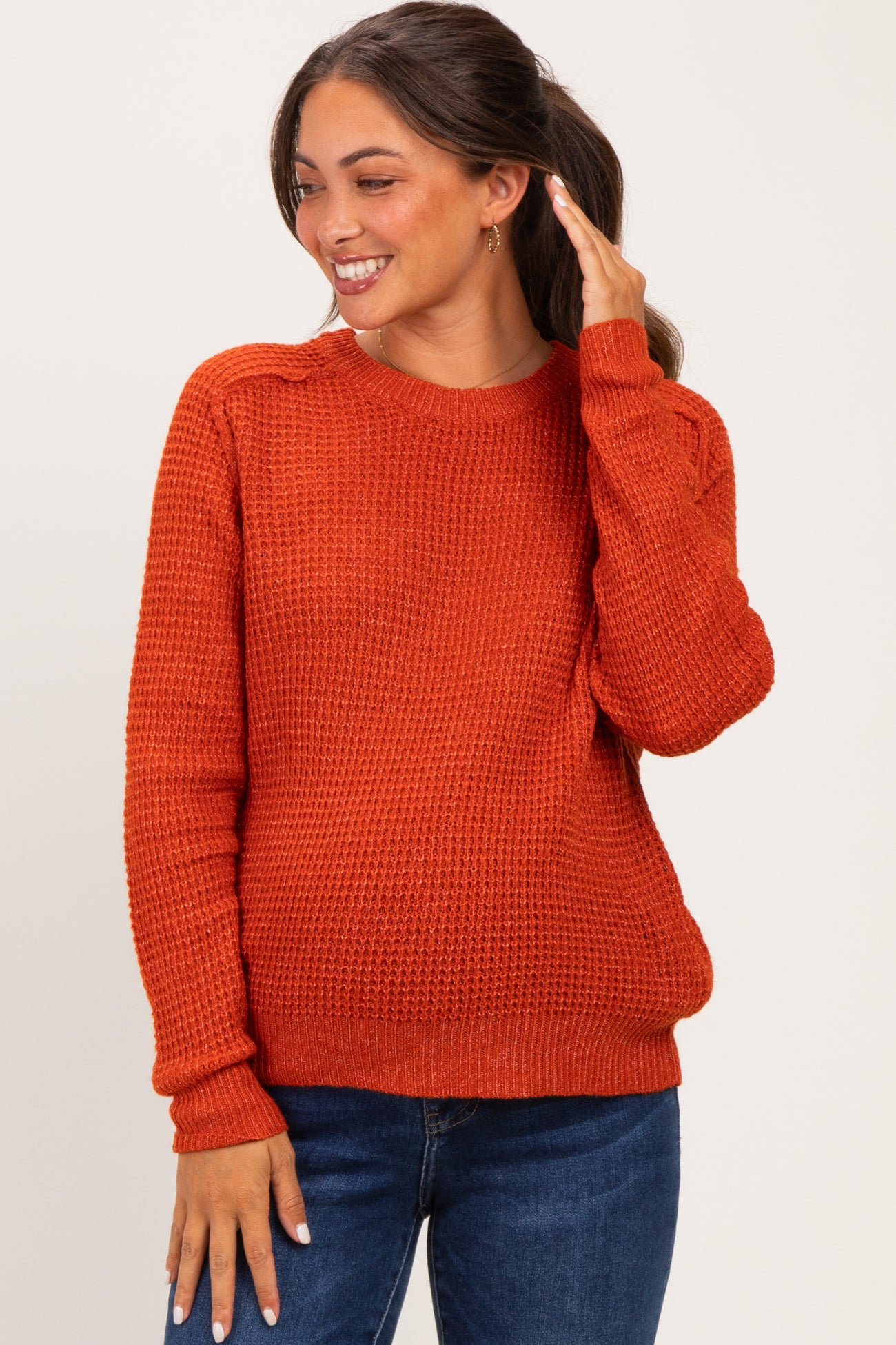 woman wearing an orange knit maternity sweater with long sleeves and a relaxed fit