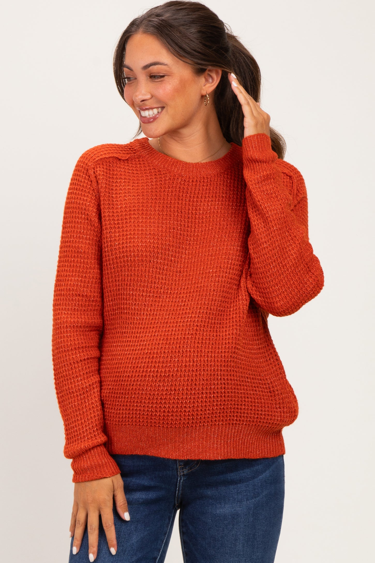 woman wearing an orange knit maternity sweater with long sleeves and a relaxed fit
