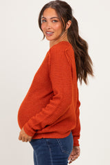 woman wearing an orange knitted maternity sweater with a visible baby bump