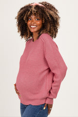 woman wearing a pink textured maternity sweater and showing her baby bump