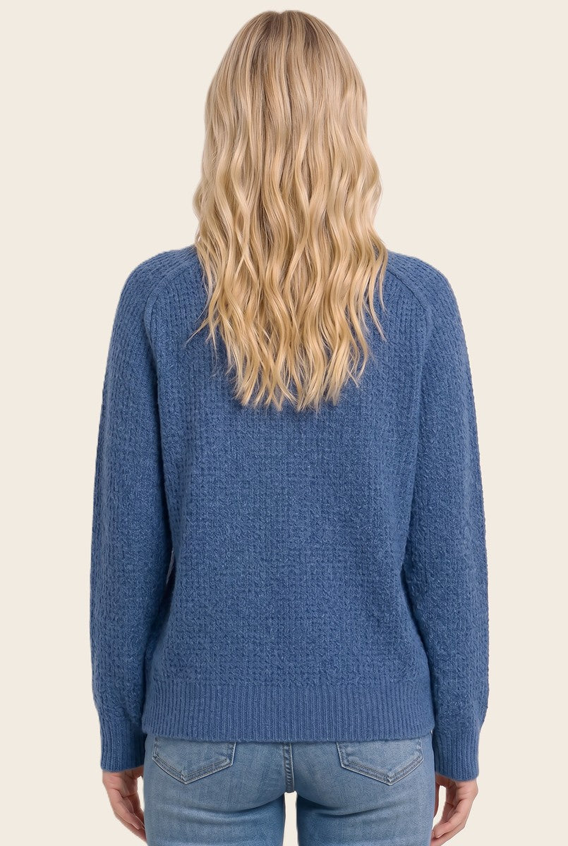 woman wearing a blue textured sweater with a relaxed fit, viewed from the back paired with denim jeans