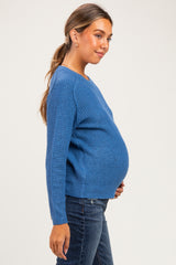 woman wearing a blue textured maternity sweater showcasing her baby bump with a side profile view