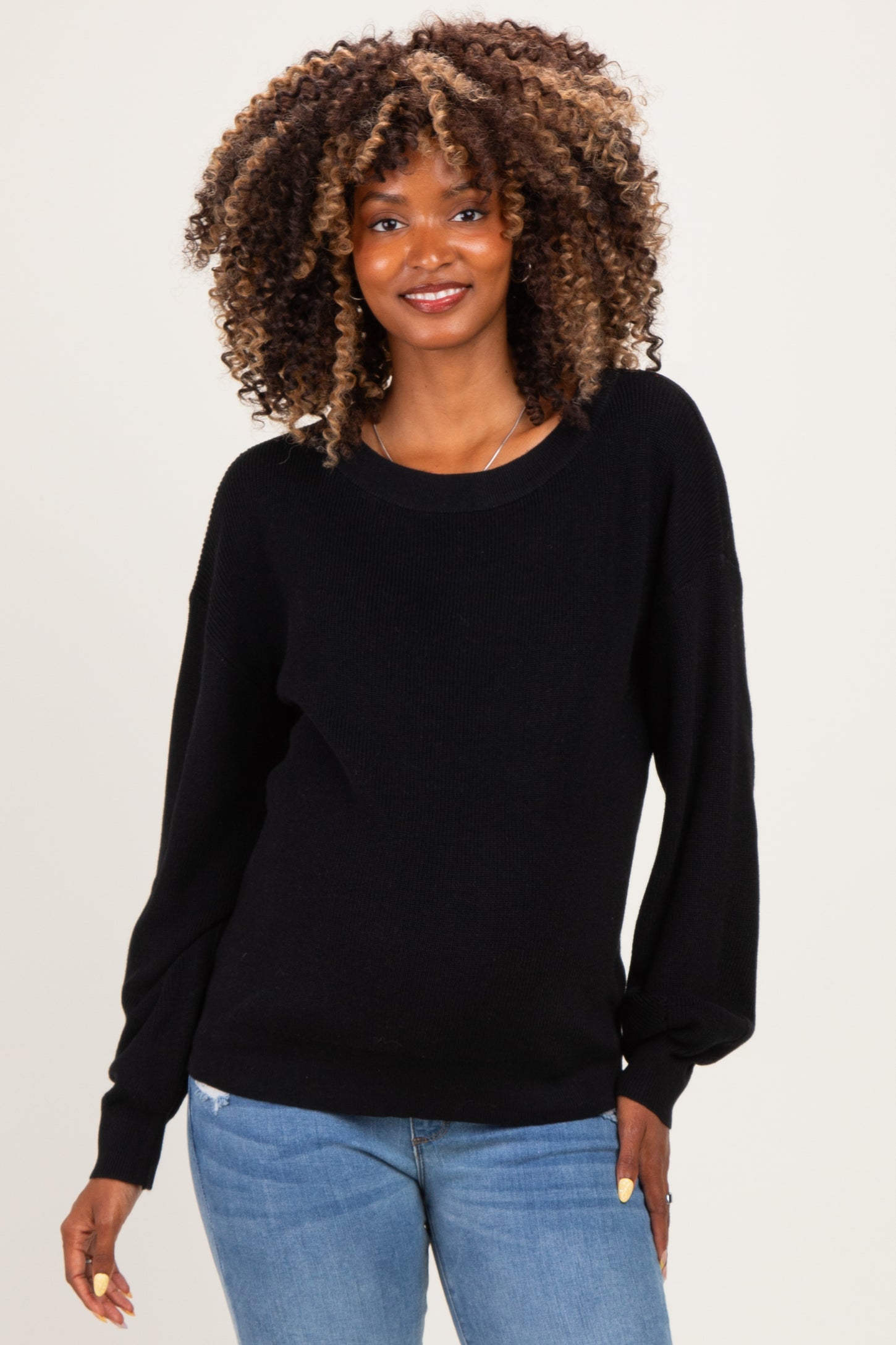 woman wearing a black long sleeve maternity sweater paired with light blue jeans