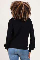 woman wearing a black maternity sweater with a relaxed fit, shown from the back, paired with light blue jeans