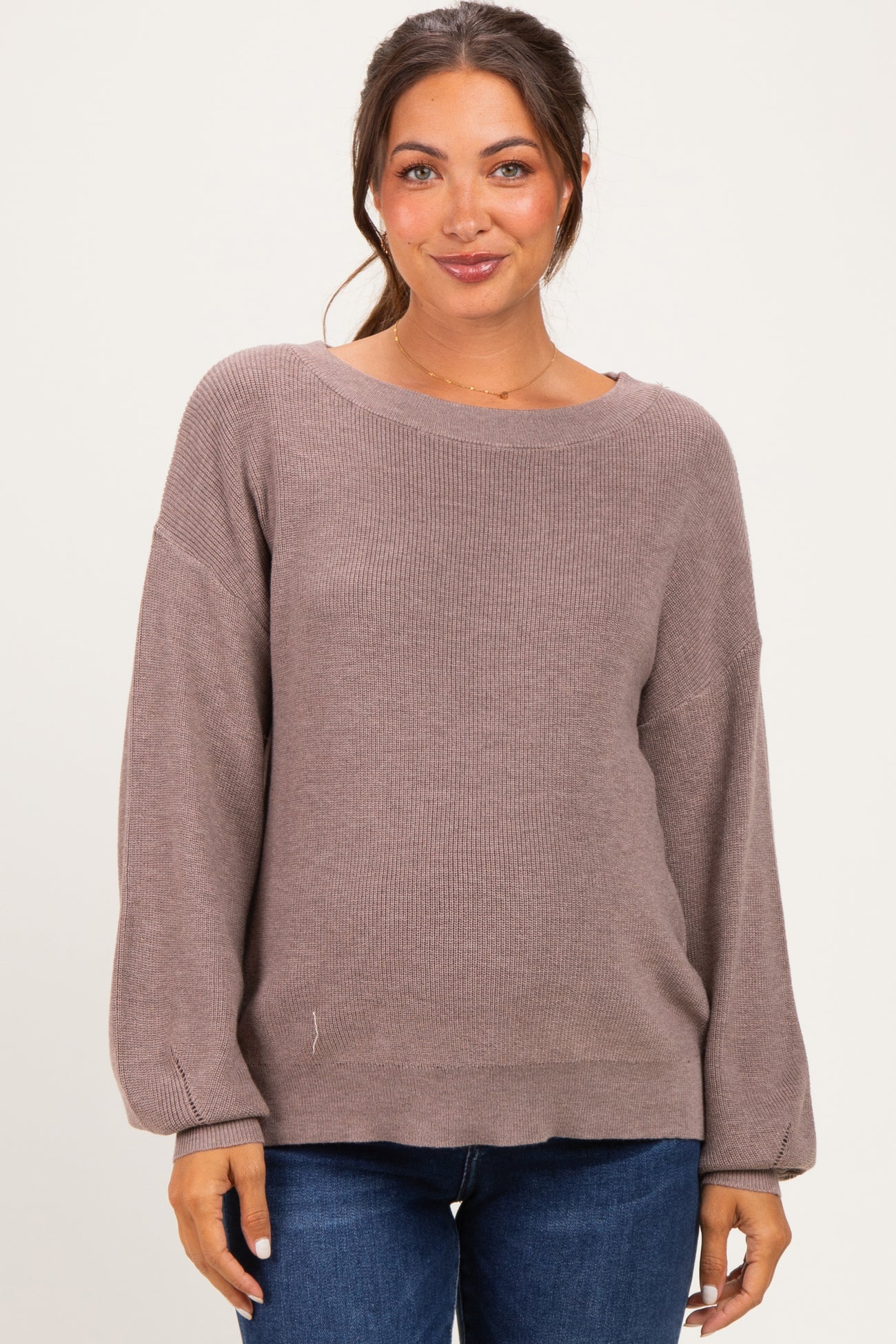 woman wearing a mauve maternity sweater with a relaxed fit and long sleeves, styled with blue jeans