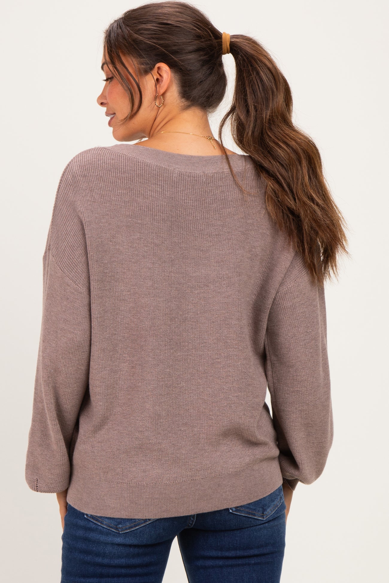 woman wearing a loose-fitting mauve maternity sweater with a relaxed back and long sleeves, styled with jeans