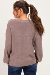 woman wearing a loose-fitting mauve maternity sweater with a relaxed back and long sleeves, styled with jeans