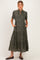 woman wearing a green floral print short sleeve maternity dress with pockets and a tiered skirt