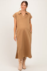 woman wearing a tan maternity dress with a collar and side pockets, showcasing her baby bump