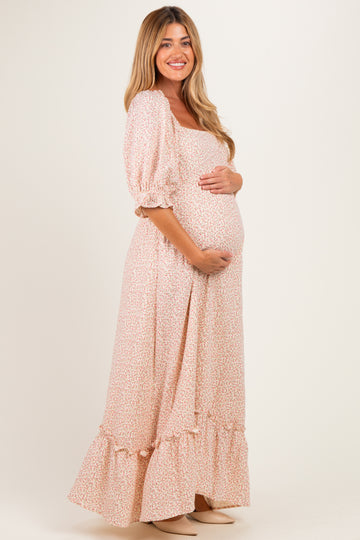 woman wearing a floral maternity maxi dress with puff sleeves and a ruffled hem, showcasing her baby bump