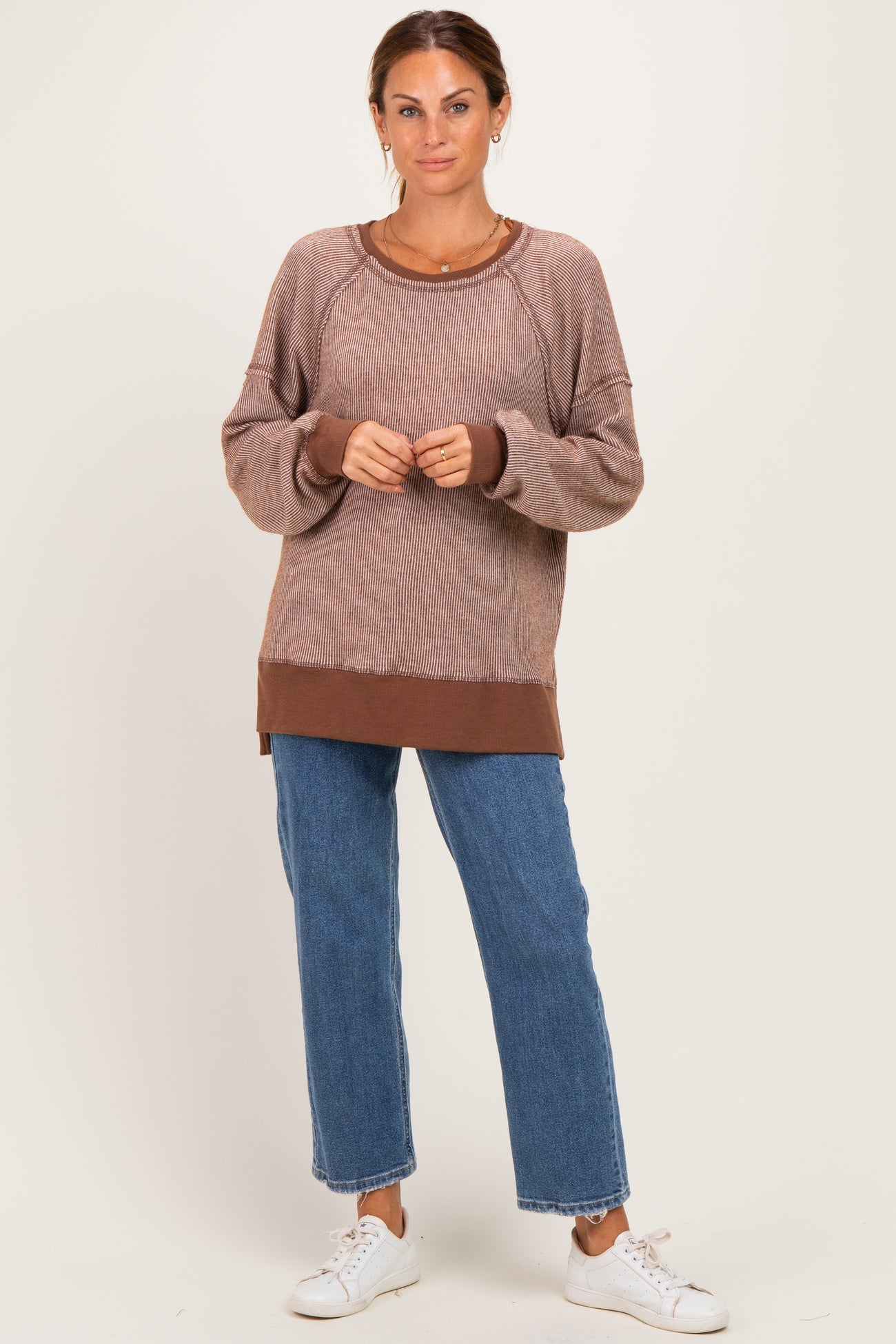 woman wearing a brown and beige ribbed long sleeve sweater with a casual fit and light blue high-waisted jeans