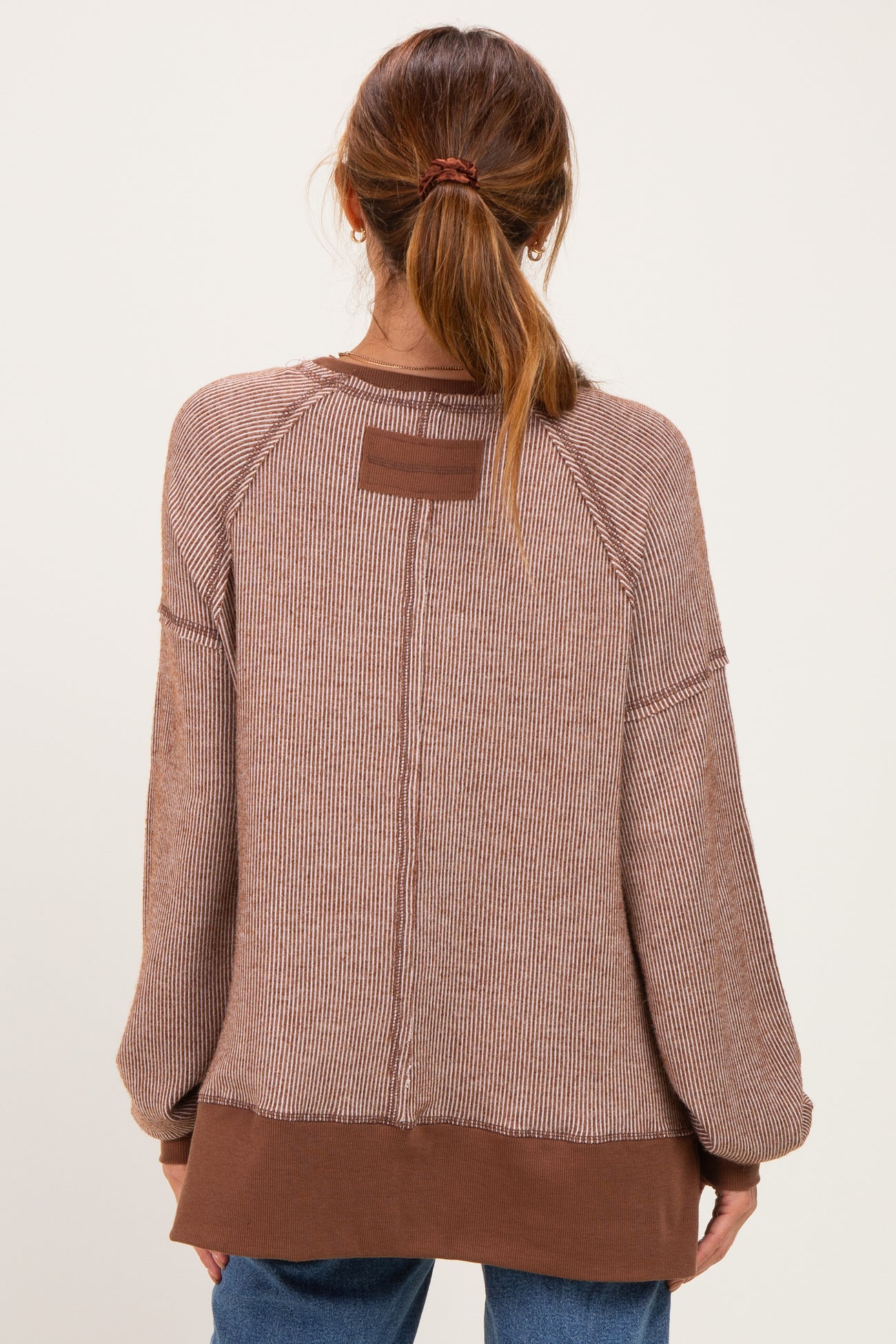 woman wearing a brown striped oversized sweater with raglan sleeves and a contrasting hem, shown from the back