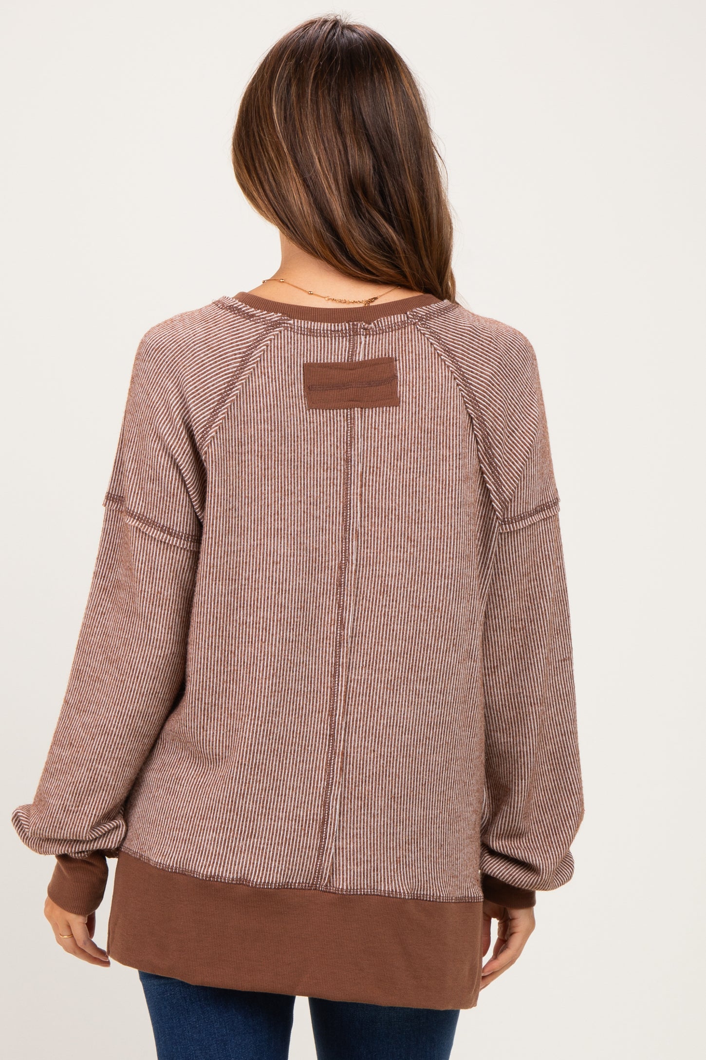 woman wearing a brown striped maternity sweatshirt with a relaxed fit and contrasting color hem