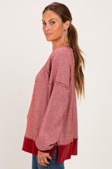 woman wearing a red and white striped oversized blouse with long sleeves and a solid red hem, styled with casual jeans