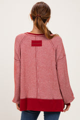 woman wearing a red striped oversized sweater with a solid red hem and back detail, styled with jeans