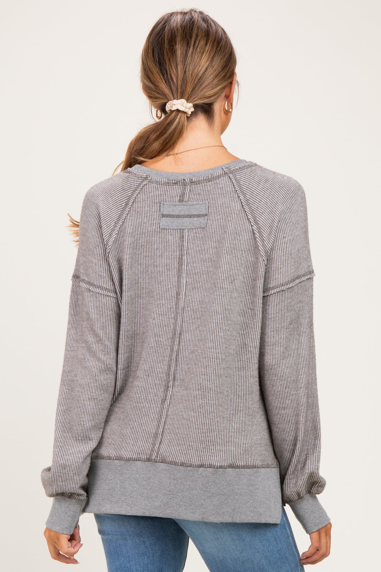 woman wearing a gray striped long sleeve maternity top, showing the back view with ribbed details