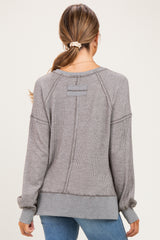 woman wearing a gray striped long sleeve maternity top, showing the back view with ribbed details