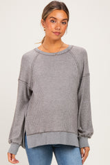 woman wearing a gray striped maternity sweater with long sleeves and side slits, styled with blue jeans