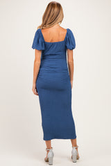 woman wearing a blue maternity dress with puff sleeves and a fitted silhouette, showing her back