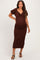 woman wearing a brown smocked maternity dress with short puff sleeves and a knot detail, showing her baby bump