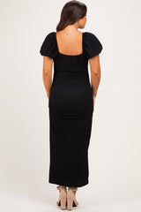 woman wearing a black maternity maxi dress with puff sleeves and a fitted silhouette, showing her baby bump from the back