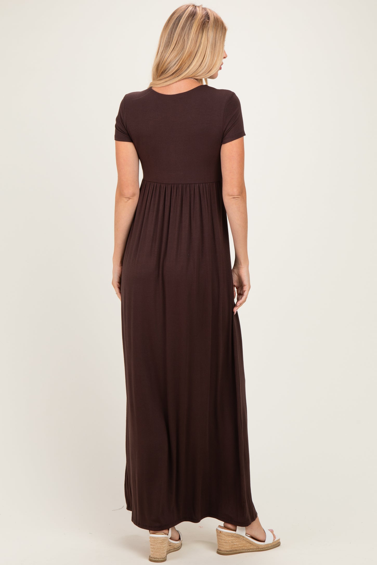woman wearing a brown maxi dress with a fitted bodice and flared skirt, viewed from the back