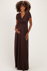 woman wearing a chocolate brown short sleeve maternity maxi dress and holding her baby bump
