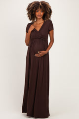 woman wearing a dark brown short sleeve maternity dress, gently holding her baby bump