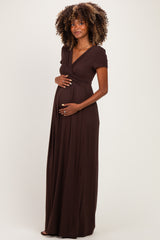 woman wearing a dark brown short sleeve maternity maxi dress and holding her baby bump