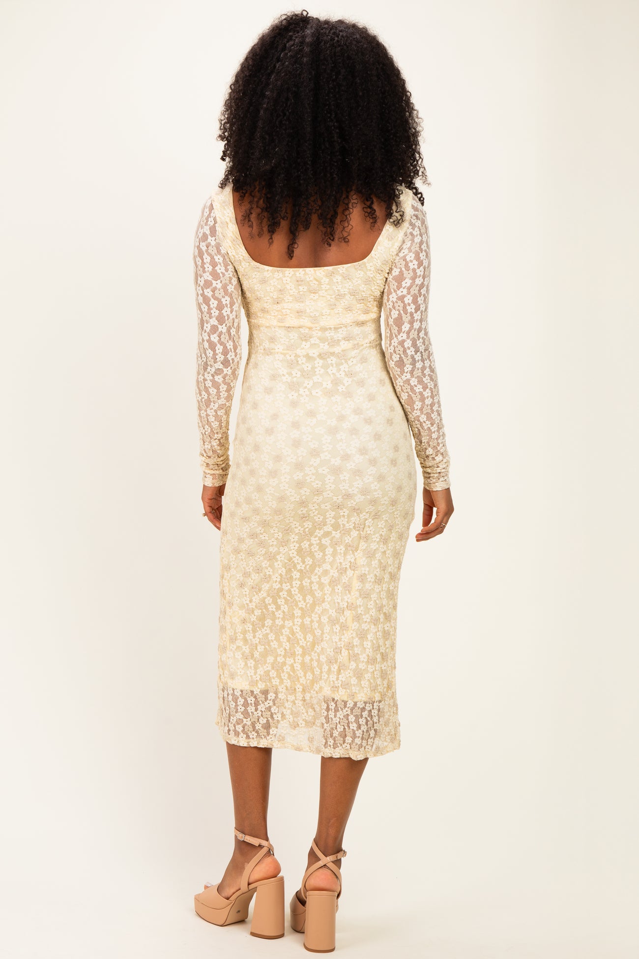 woman wearing a cream long sleeve midi dress with a lace overlay and fitted silhouette, showing the back view
