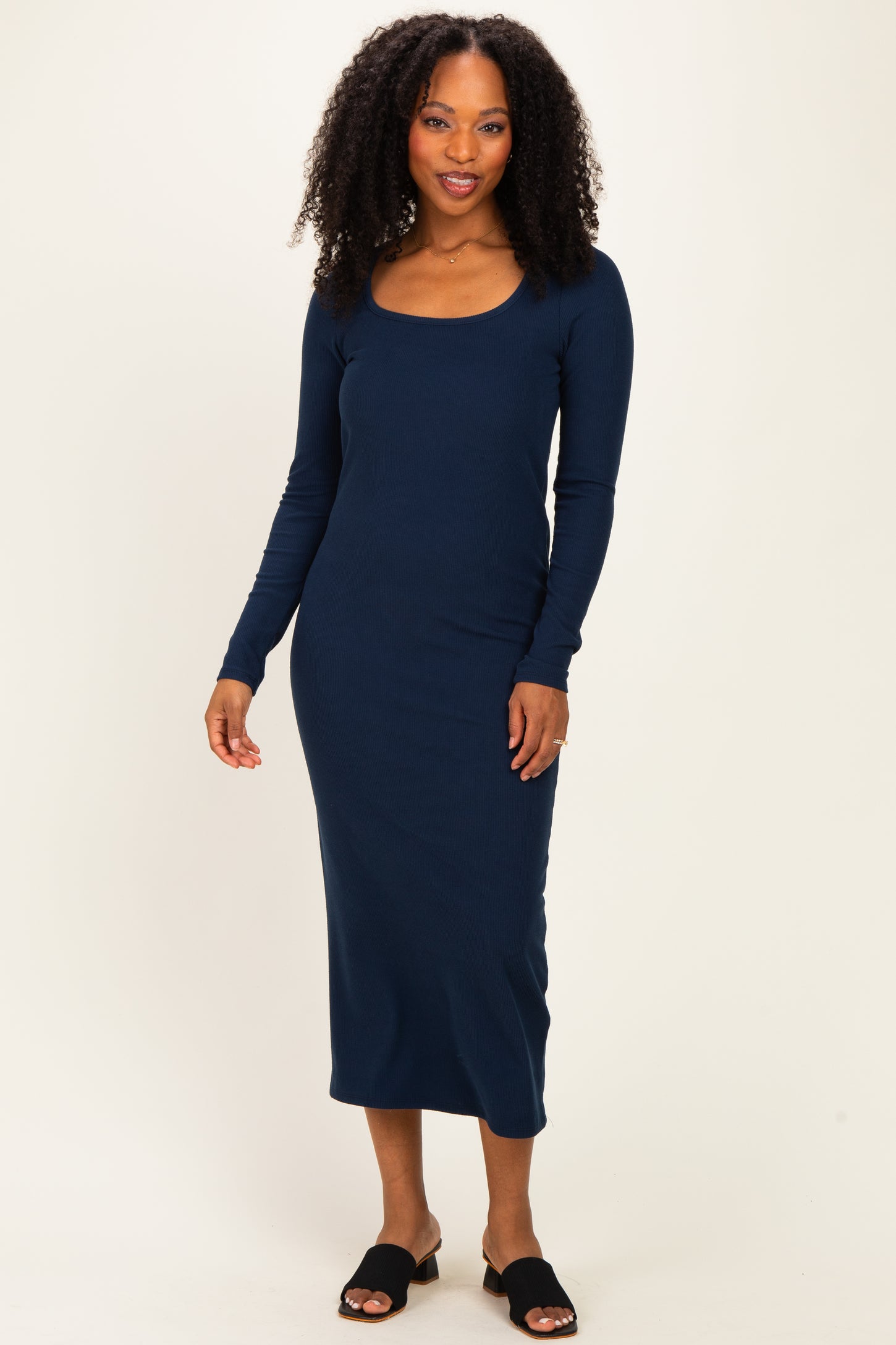 woman wearing a navy long sleeve ribbed dress with a scoop neckline and black slide sandals