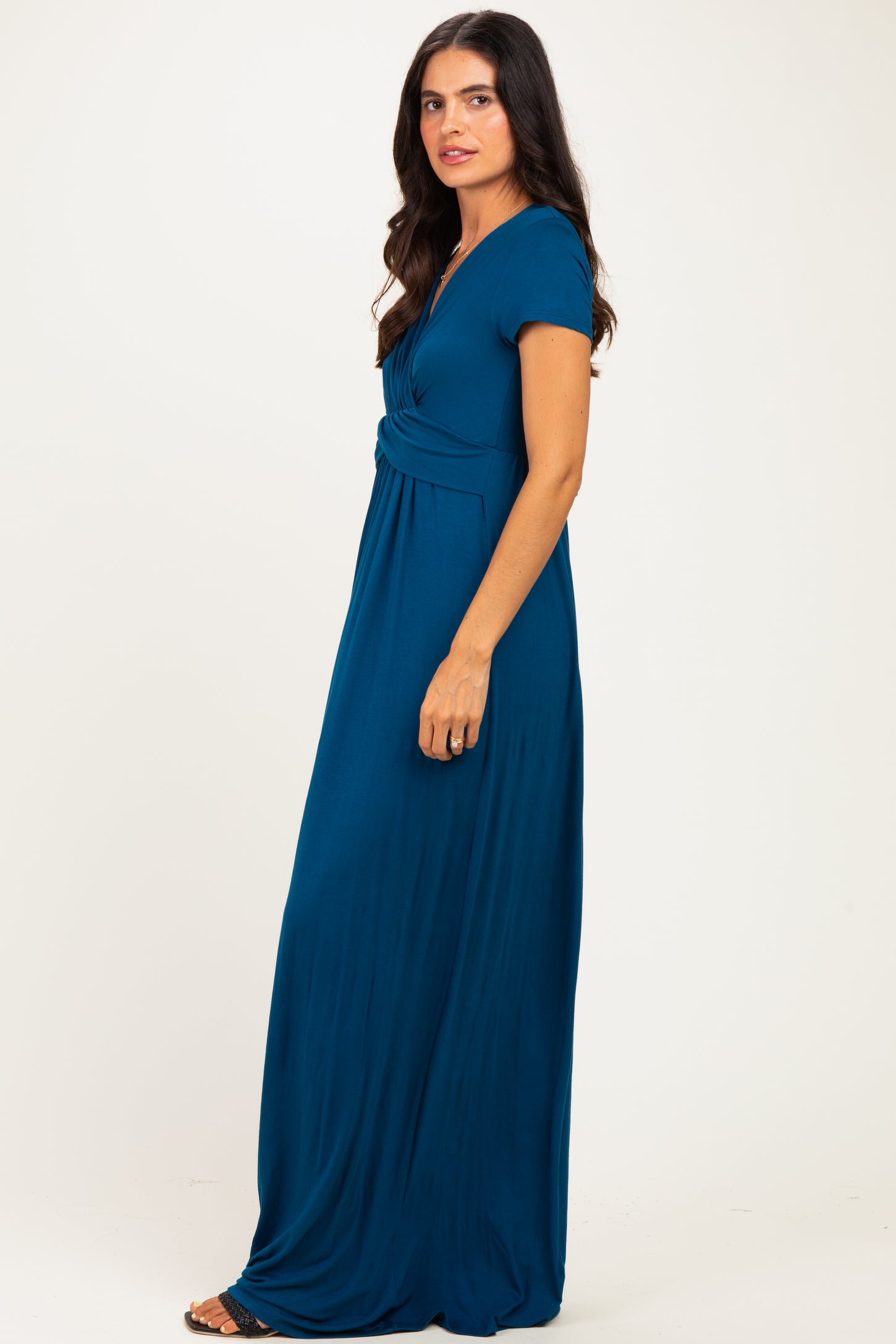 woman wearing a teal maxi dress with a twisted front detail and short sleeves