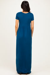 woman wearing a short sleeve teal maxi dress, showing the back view with a fitted bodice and flowy skirt