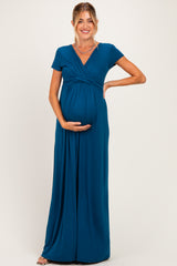 woman wearing a teal short sleeve maternity maxi dress holding her baby bump
