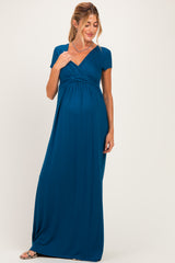 woman wearing a teal short sleeve maternity maxi dress, showcasing her baby bump and a flattering wrap design