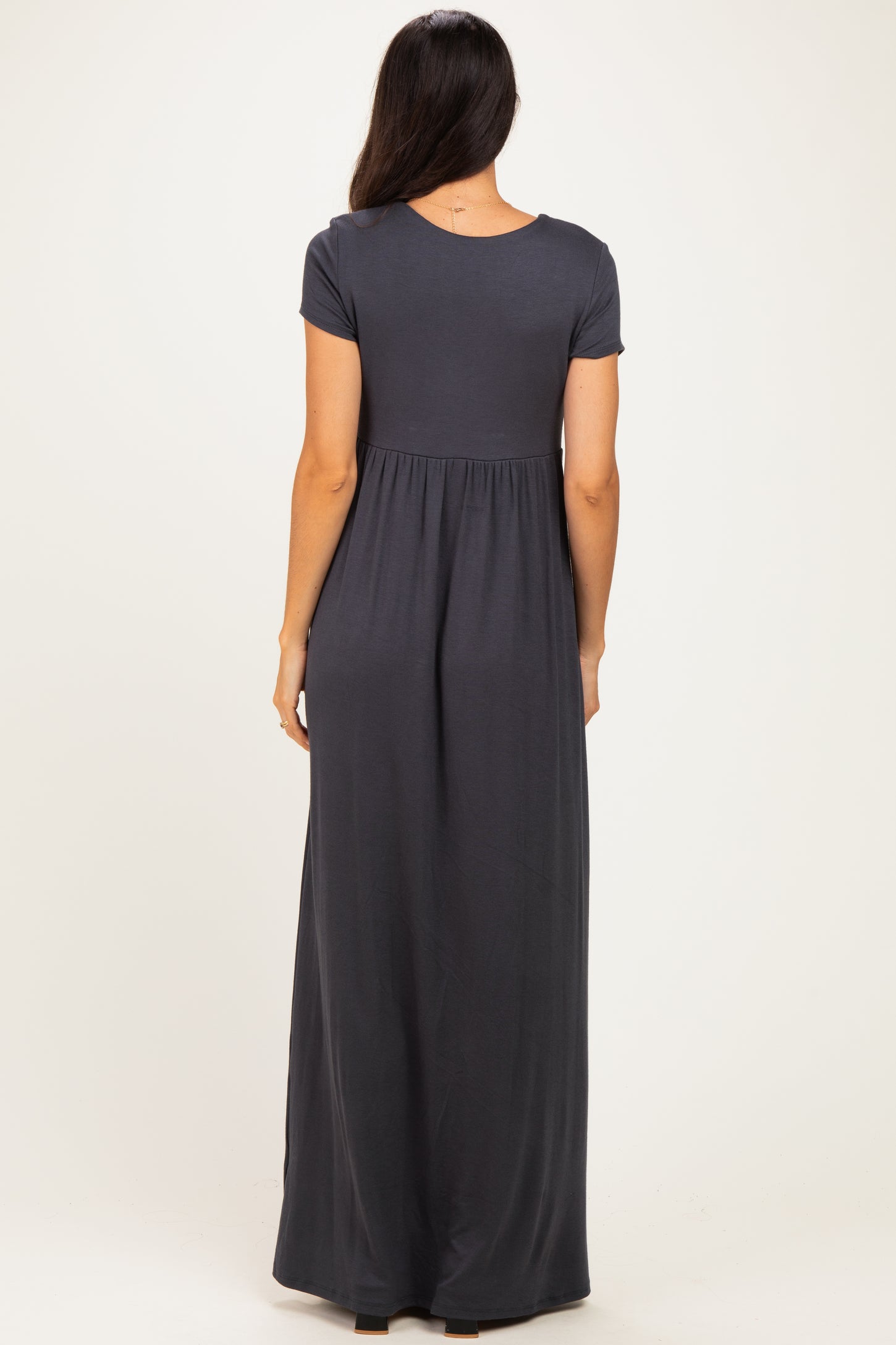 woman wearing a dark gray short sleeve maxi dress with a gathered waist and flowy skirt