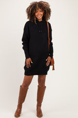 woman wearing a black knitted maternity hoodie dress, showing her baby bump, paired with brown knee-high boots