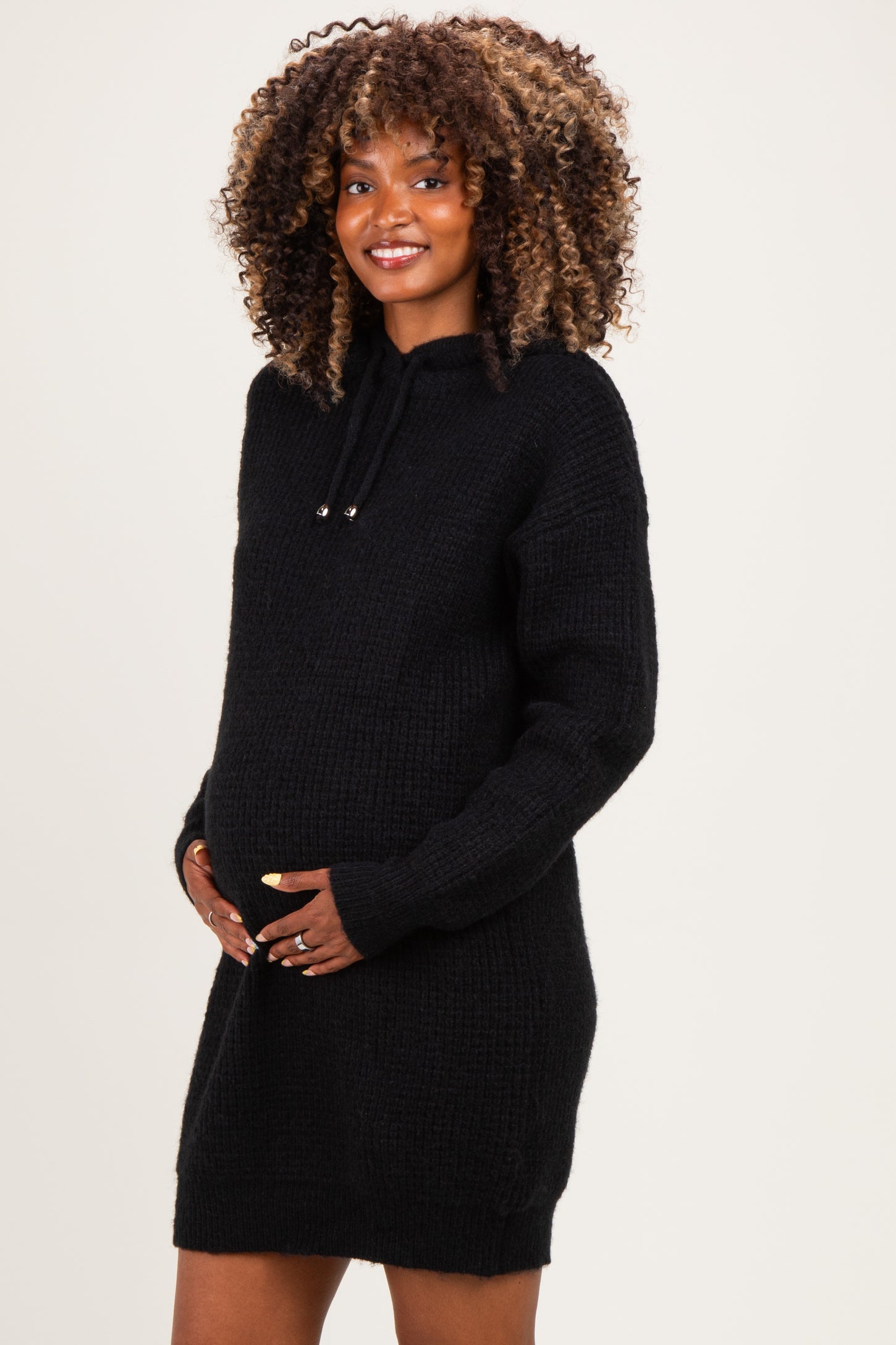 woman wearing a black maternity hoodie dress and holding her baby bump