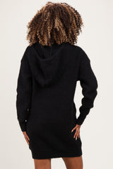 woman wearing a black knitted maternity hoodie dress, showing a relaxed fit and hood in the back