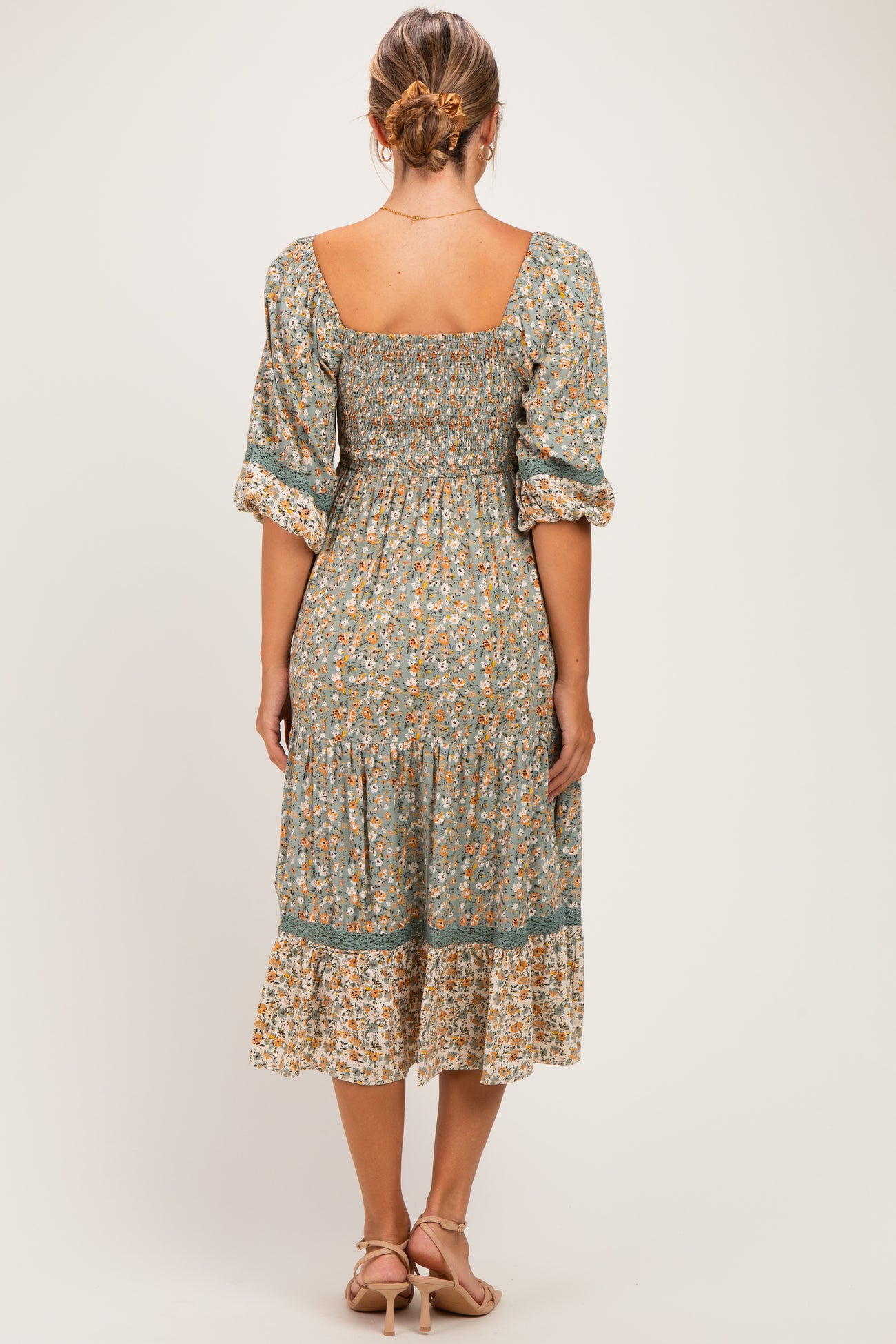 woman wearing a floral print maternity dress with a square neckline and puff sleeves, showing the back view