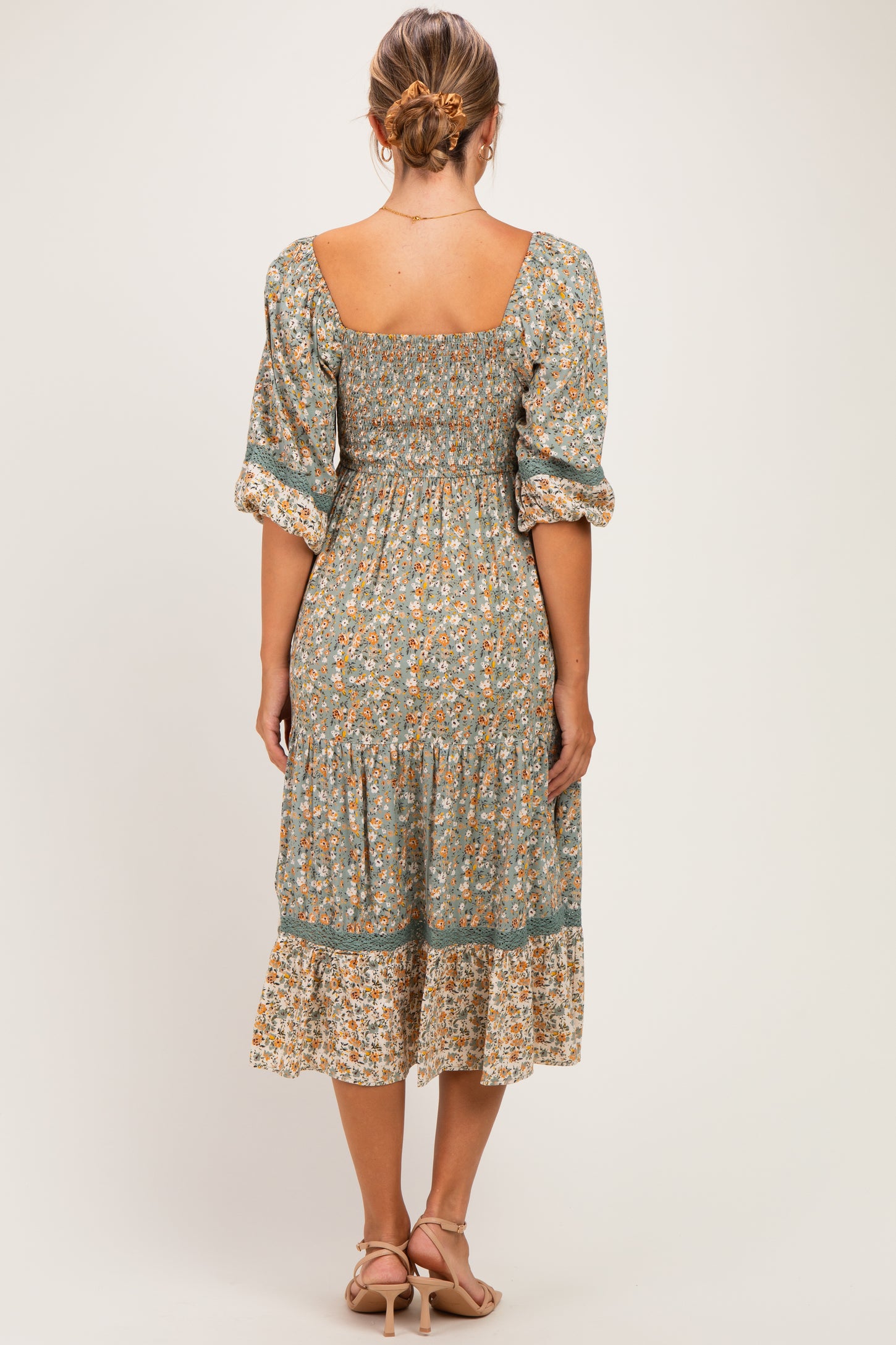 woman wearing a floral print maternity dress with a square neckline and puff sleeves, showing the back view