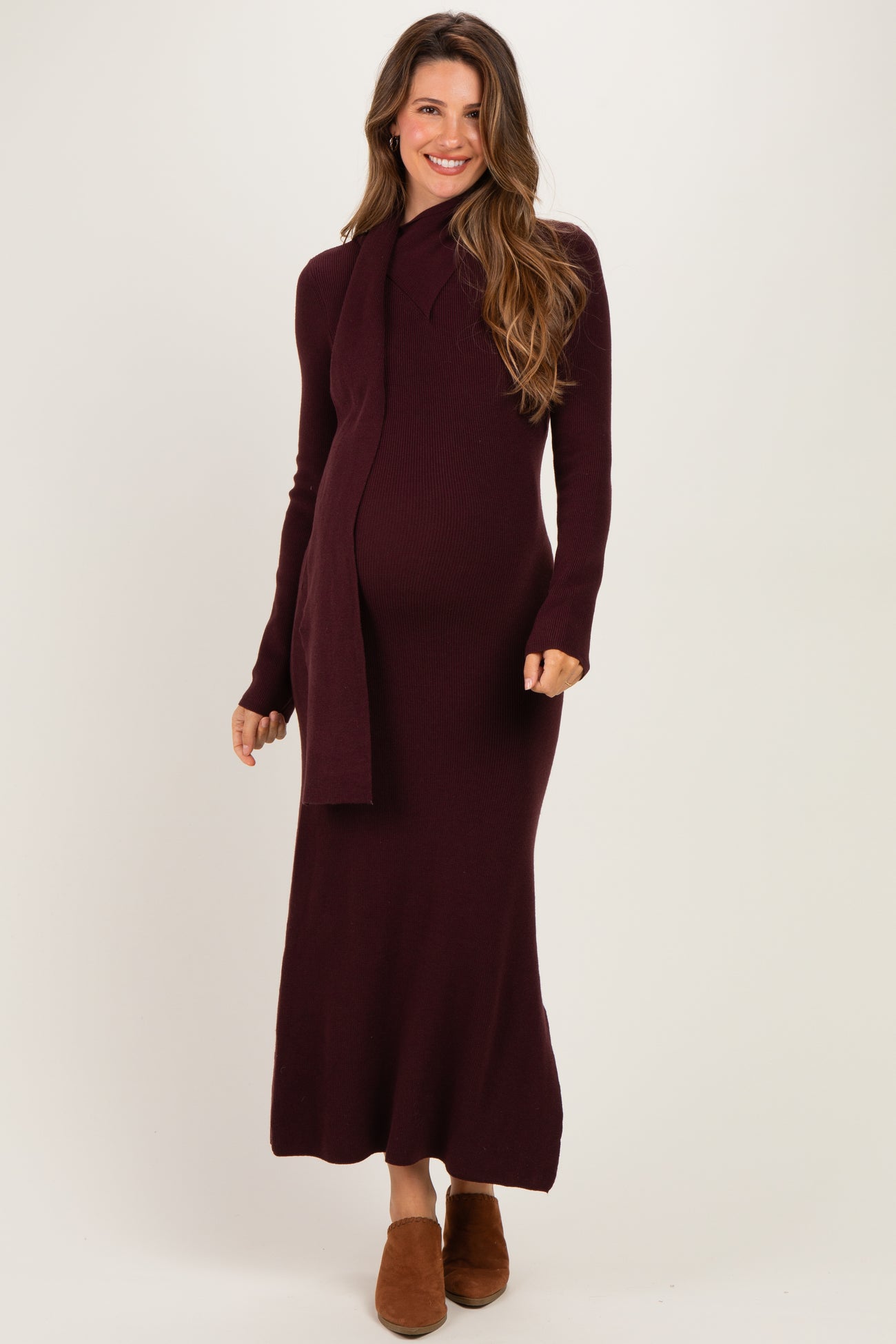 woman wearing a burgundy knit maternity dress with long sleeves and a scarf, showing her baby bump