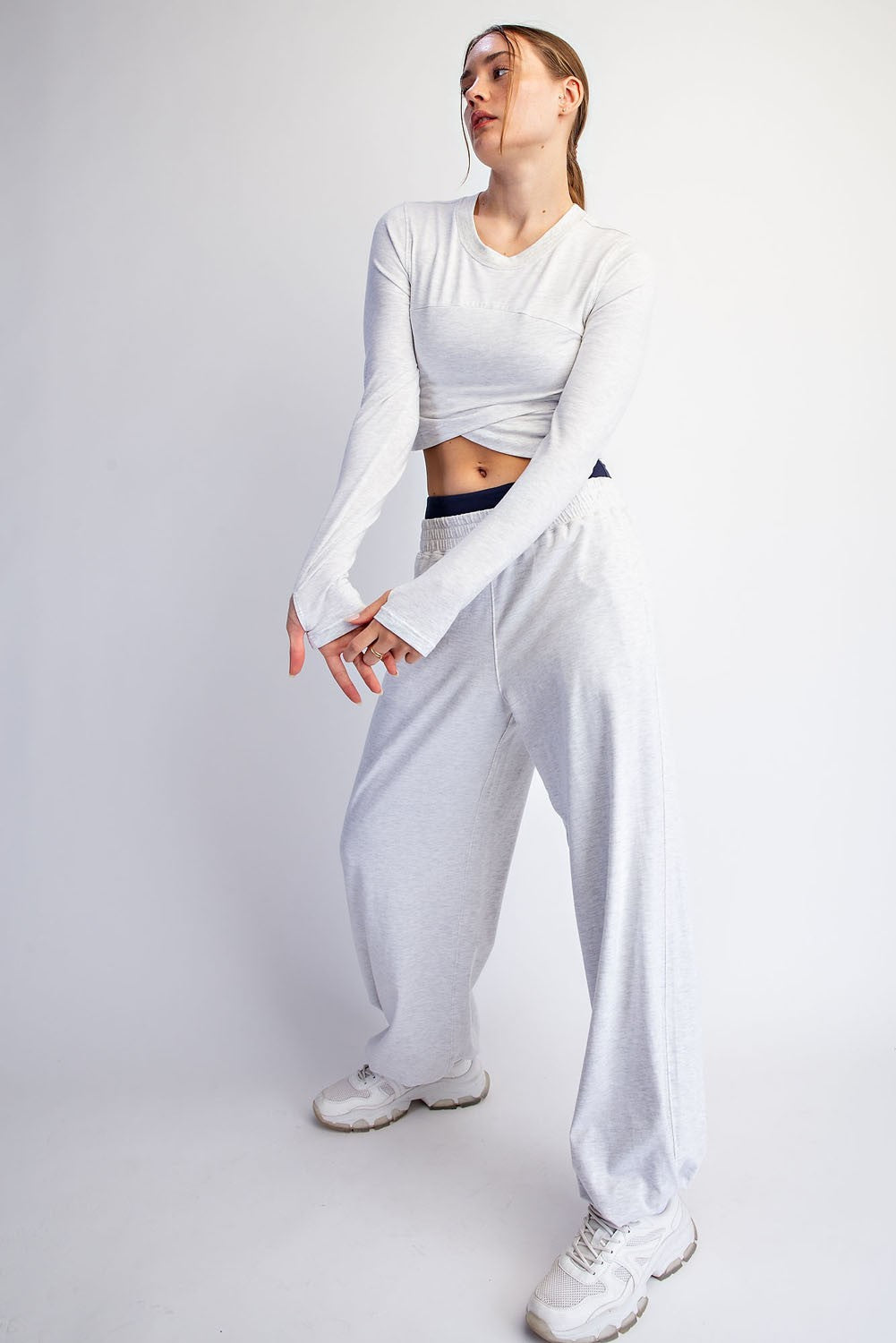 woman wearing a light gray long sleeve cropped top and matching wide-leg sweatpants with sneakers