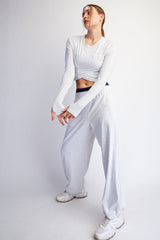 woman wearing a light gray long sleeve cropped top and matching wide-leg sweatpants with sneakers