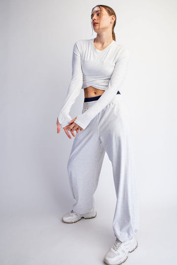 woman wearing a light gray long sleeve cropped top and matching wide-leg sweatpants with sneakers