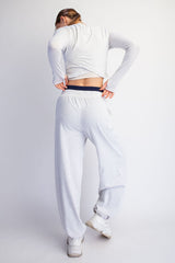 woman wearing a gray long sleeve cropped top and matching gray wide-leg sweatpants, showing her back