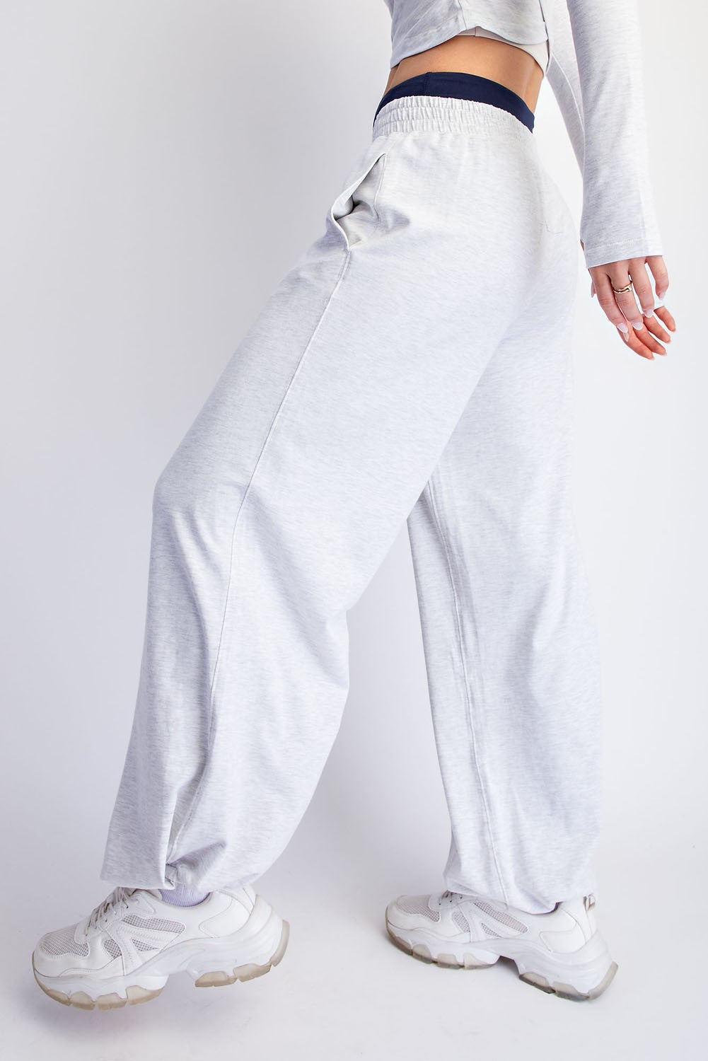 woman wearing light grey oversized sweatpants with an elastic waistband and pockets, paired with white sneakers