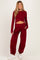 woman wearing a burgundy maternity crop top with long sleeves and matching wide-leg maternity pants