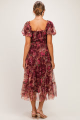 woman wearing a floral burgundy maternity dress with short puff sleeves and a tiered skirt, showing a baby bump from behind
