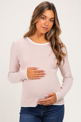 woman wearing a pink and white striped maternity long sleeve top and holding her baby bump